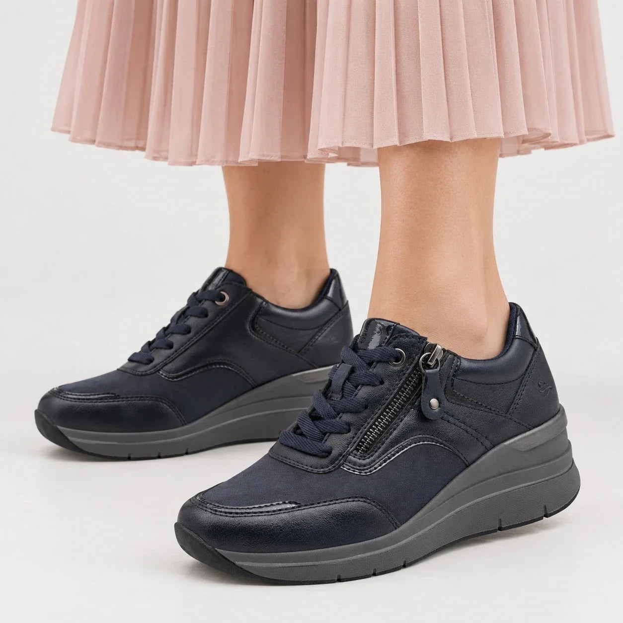 Jana Softline navy wide-fit wedge trainers with laces and side zip, worn with a pale pink pleated skirt