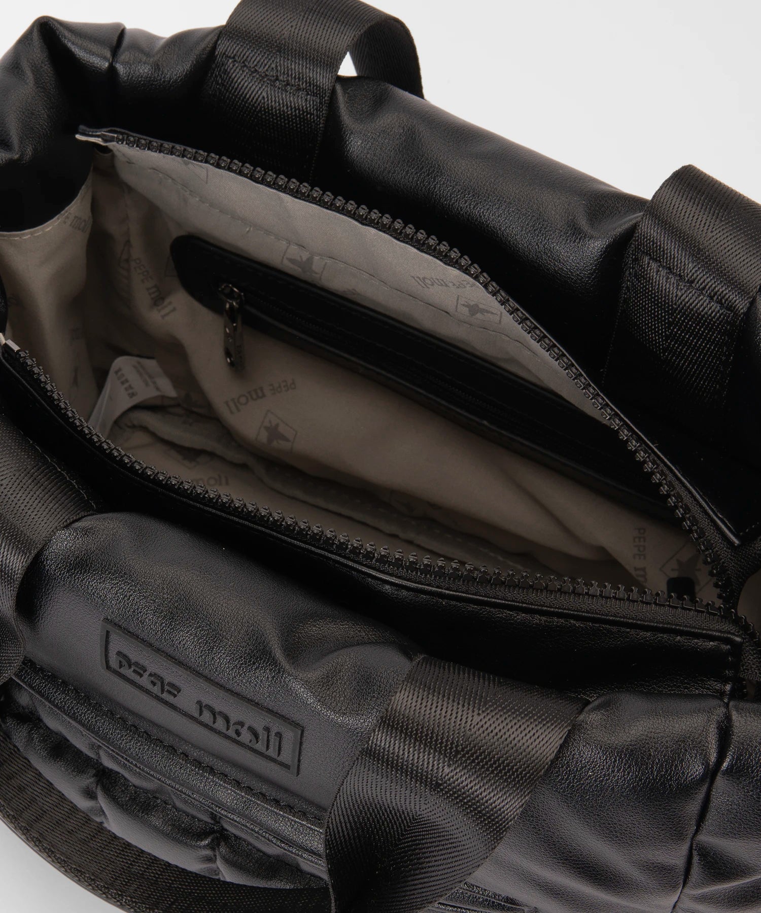 Close-up of a black backpack with visible branding on a light gray background