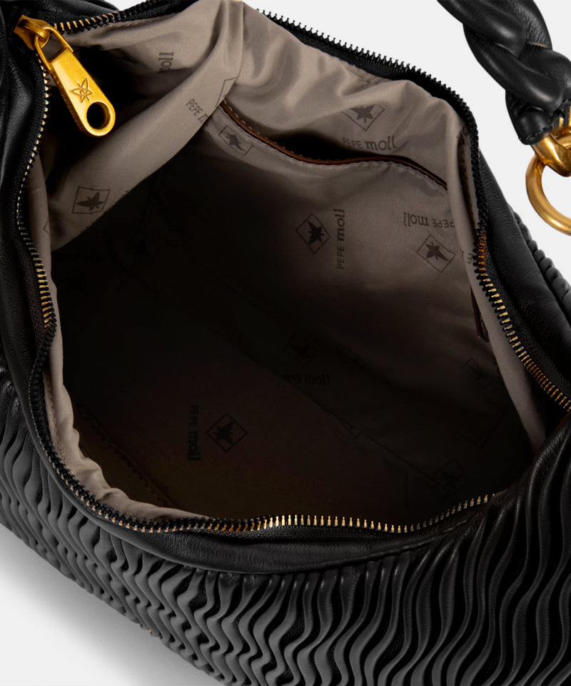 Close-up of a textured black handbag with gold zipper and hardware.
