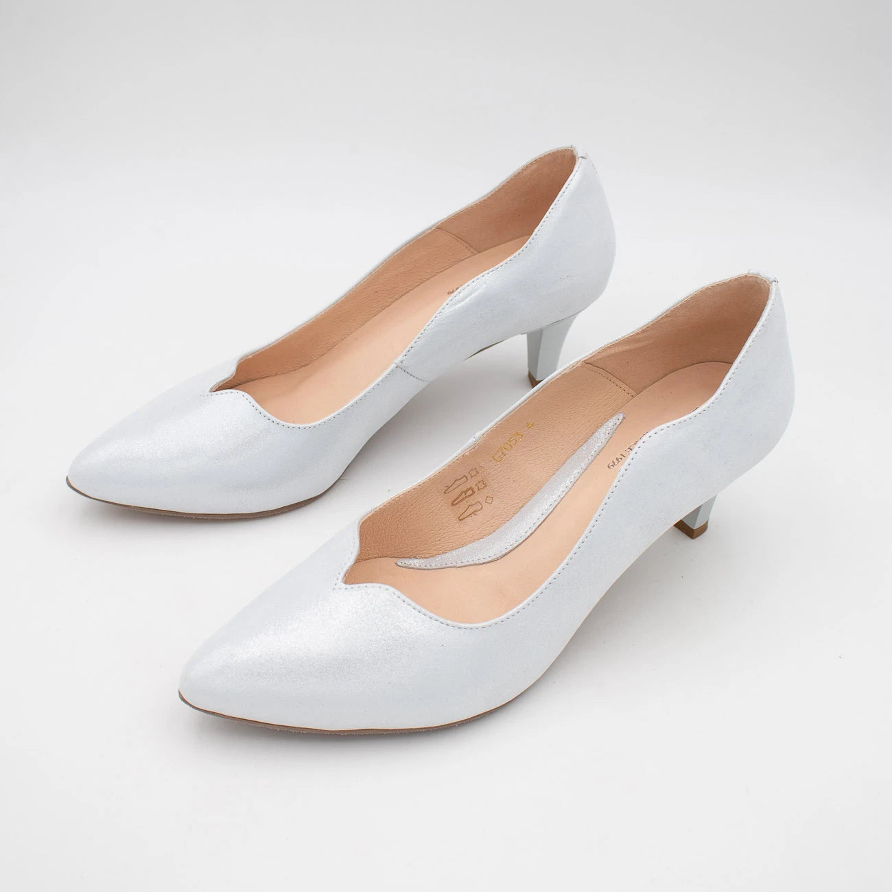 Pair of white high-heeled shoes on a light gray background