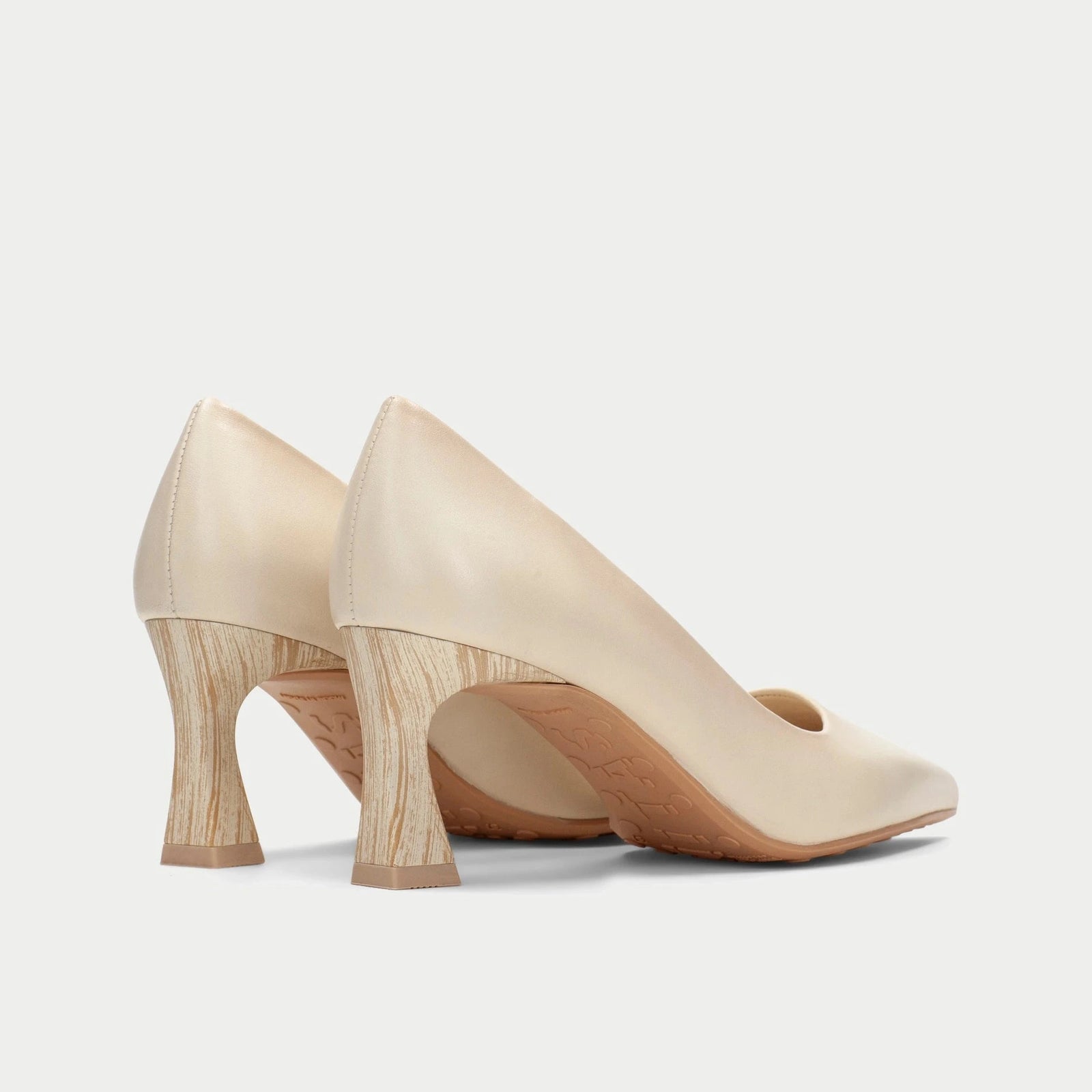 Pair of beige high-heeled shoes on a light gray background