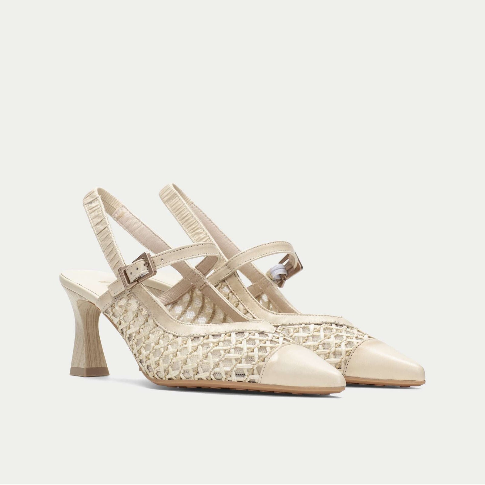Beige high-heeled shoes with a woven design on a light beige background