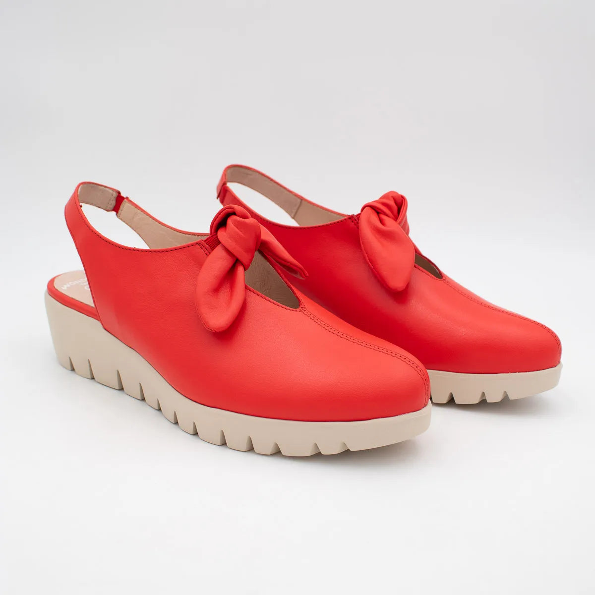 Red platform shoes with bow details on a white background