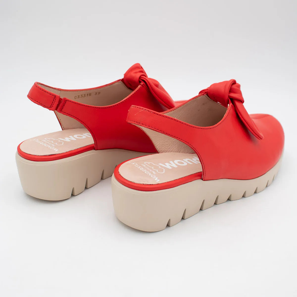 Red platform sandals with bow details on a white background