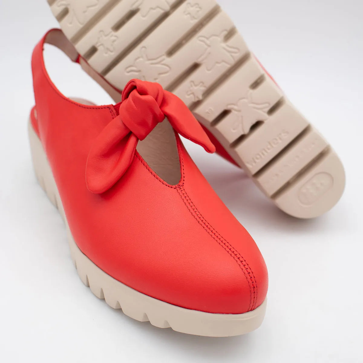 Red shoe with a bow and beige sole on a white background