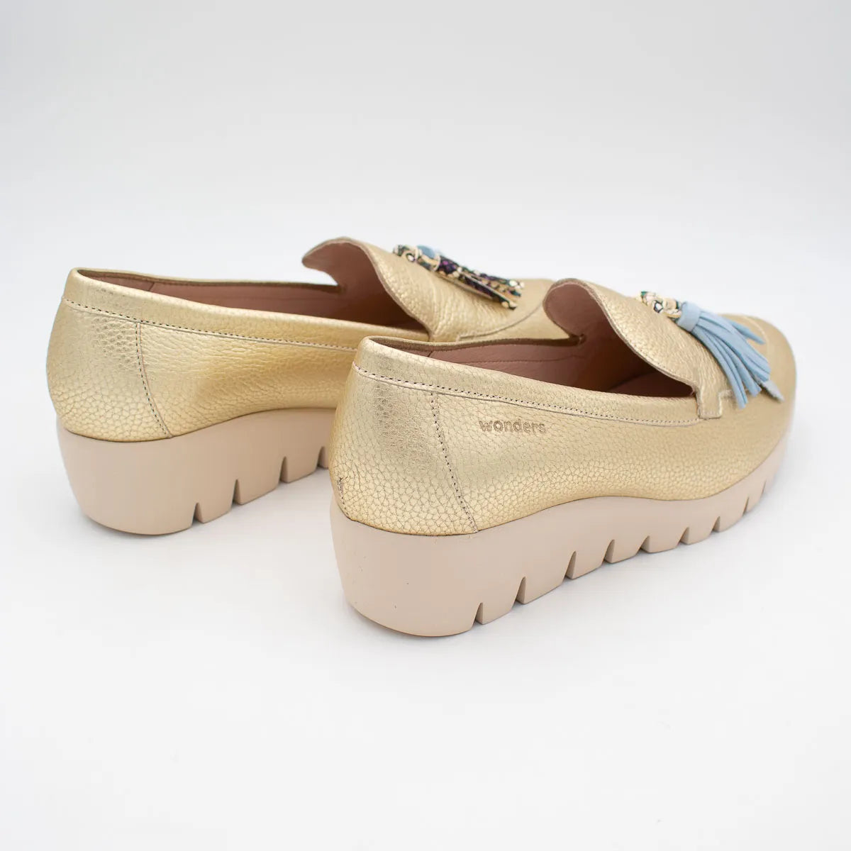 Gold loafers with decorative elements on a white background