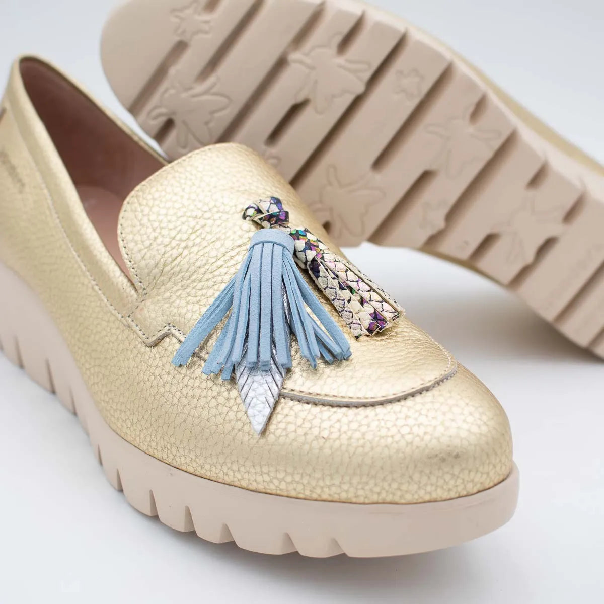 Beige loafer shoe with a decorative tassel on a light background
