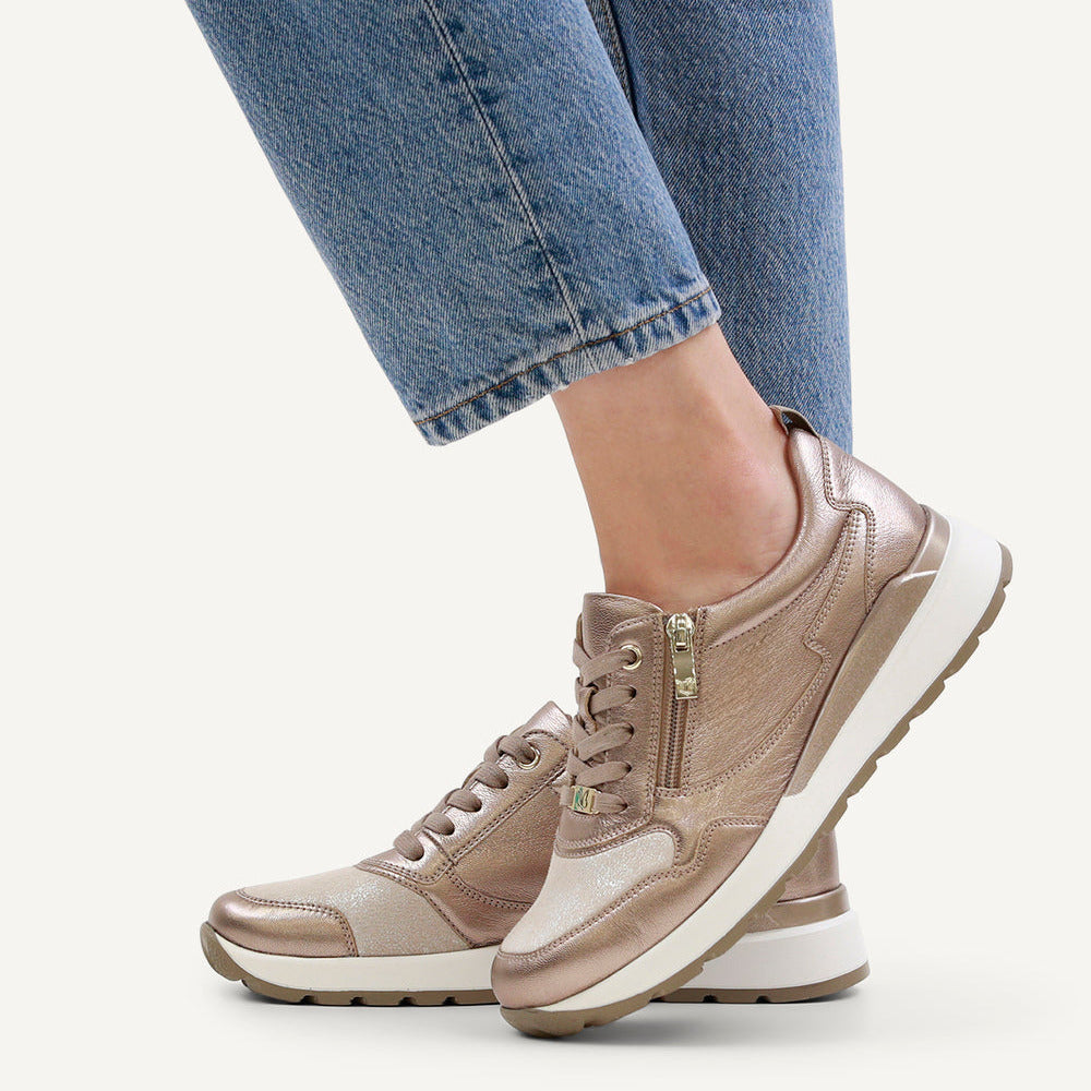 Beige sneakers worn with blue jeans on a white background