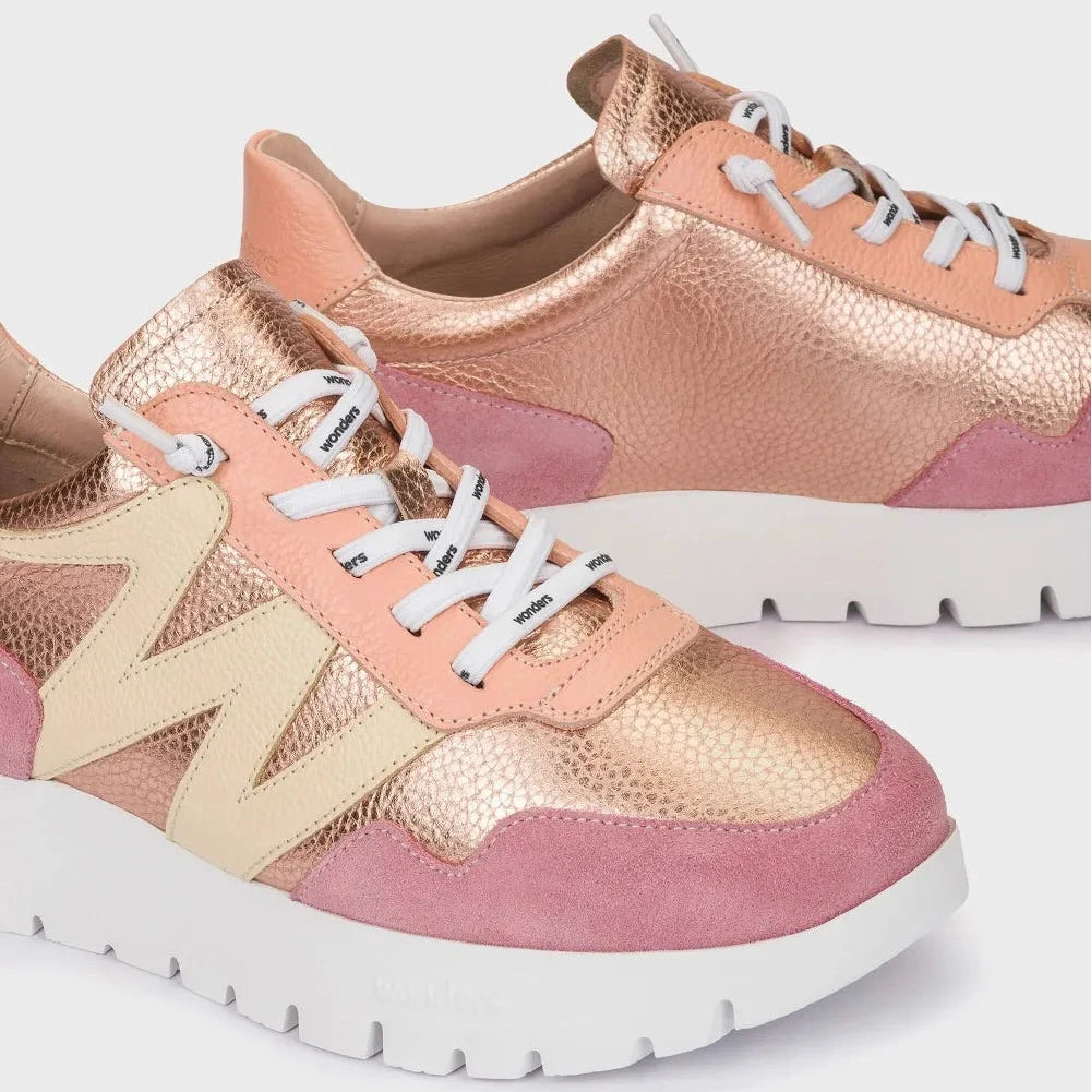 Pair of pink and rose gold sneakers with white laces on a light gray background