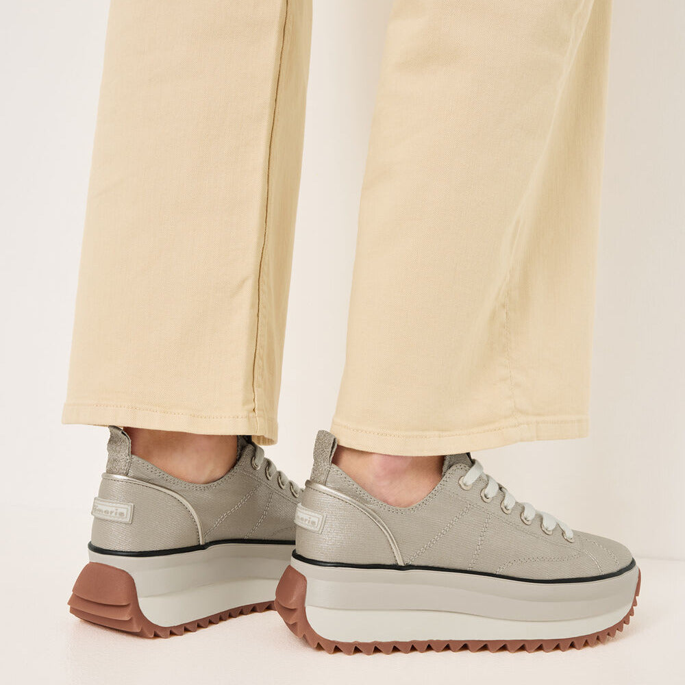 Light gray sneakers with brown soles worn with beige pants on a light background