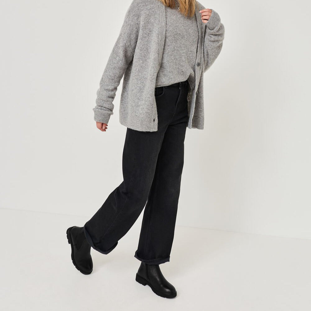Person wearing a gray cardigan, black pants, and black shoes on a white background