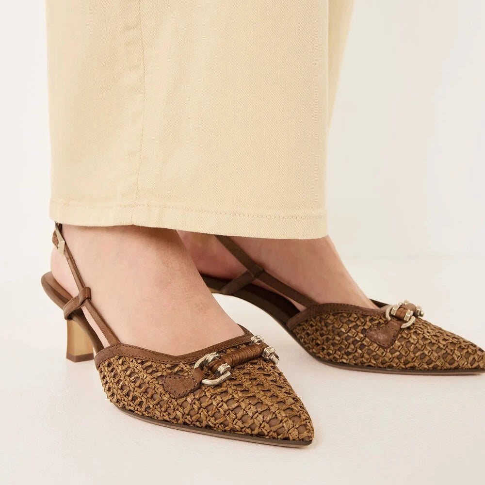 Brown woven shoes with a strap worn by a person on a light background