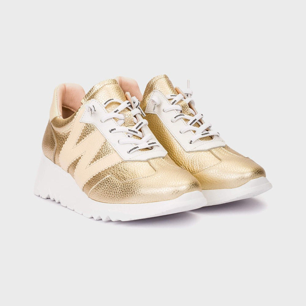 Gold sneakers with white soles on a light gray background