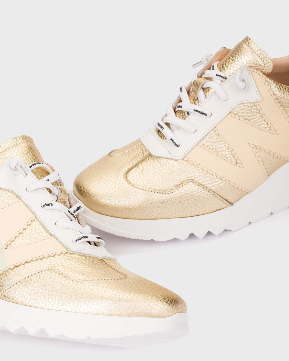 Gold sneakers with white laces on a white background