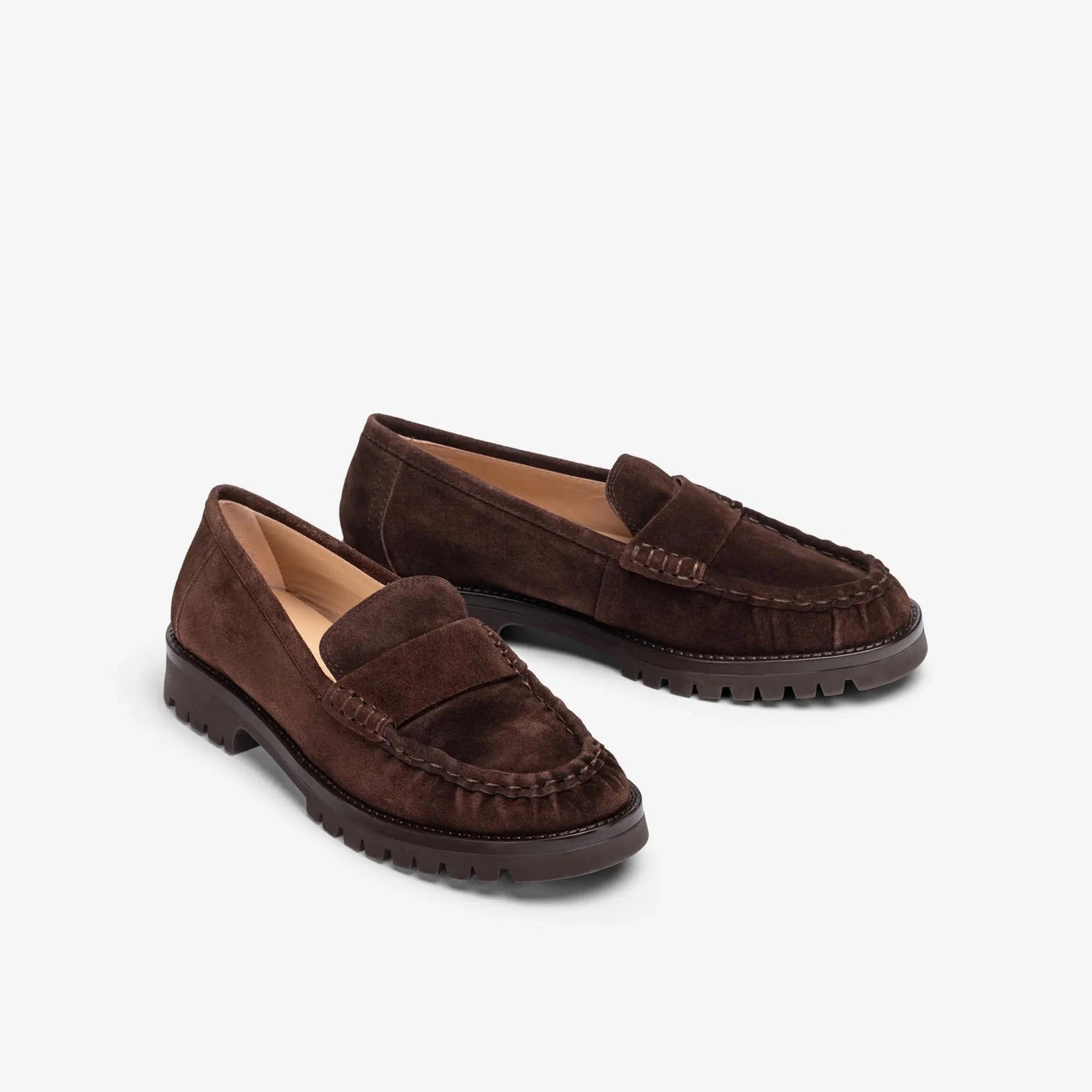 A pair of dark brown suede penny loafers with thick black lug soles, displayed on a clean white background.