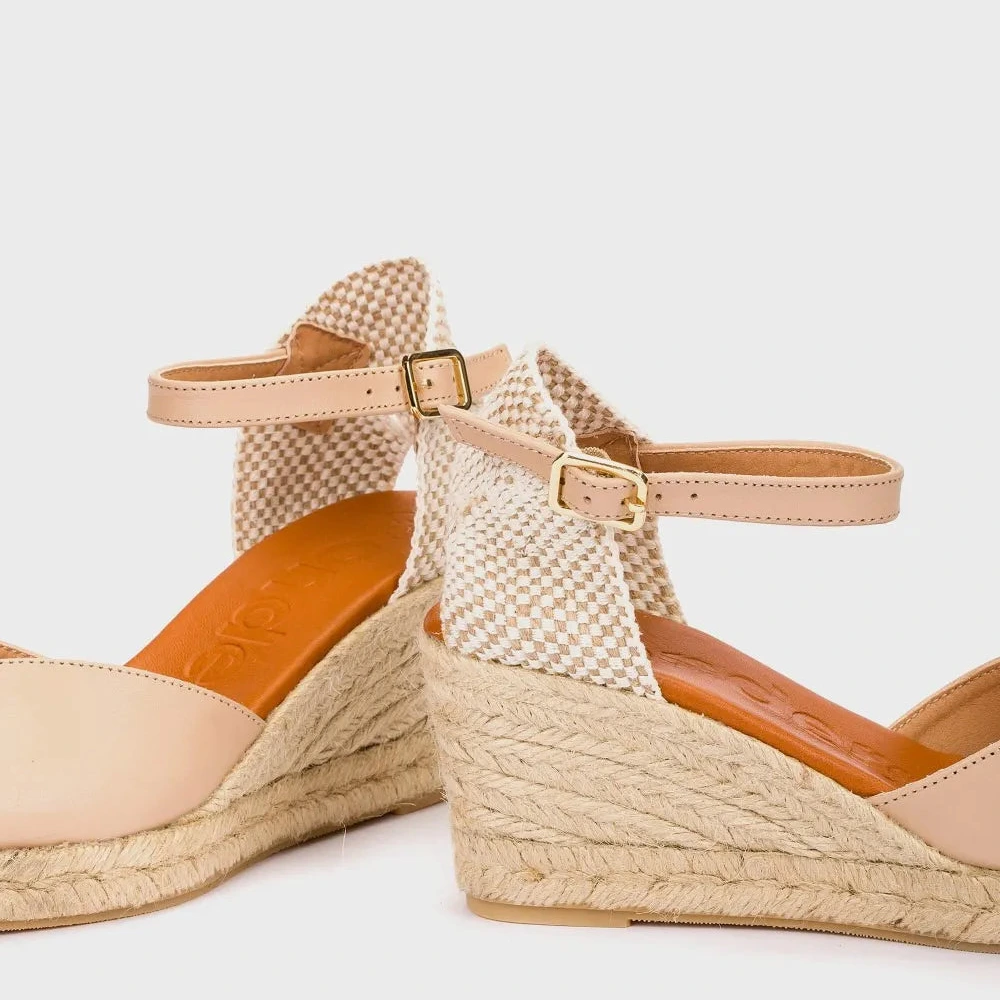 Beige wedge sandals with woven design on a white background