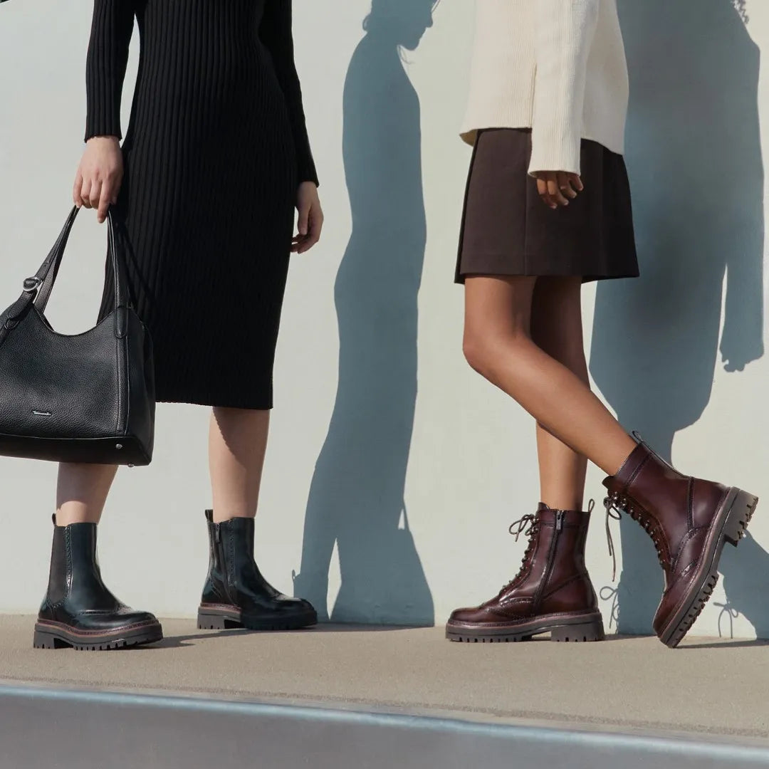 Two women wearing boots on the street.
