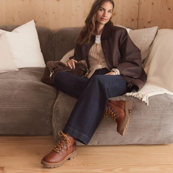 Woman wearing boots casually on a couch.