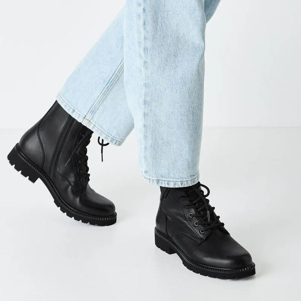 Woman wearing black lace up boot with jeans.