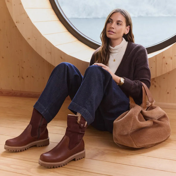 Woman sitting down wearing fur lined brown ankle boots.