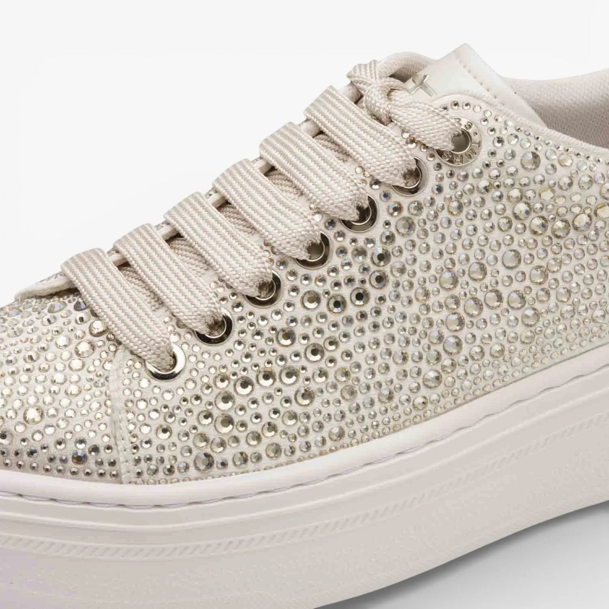 Beige sneaker with rhinestone embellishments on a white background