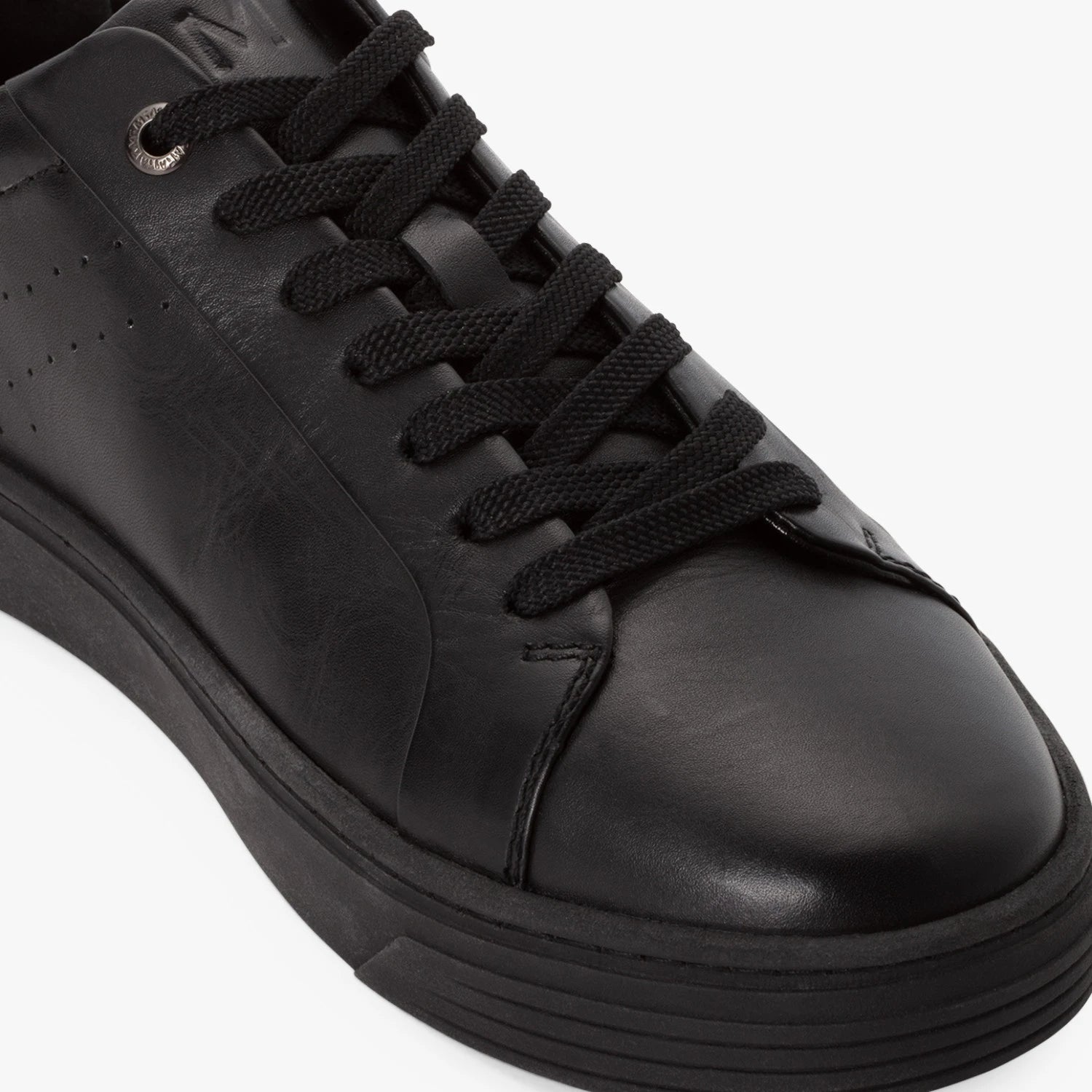 Close-up of the laces, smooth leather and tonal stitching on the black Marco Tozzi trainer.