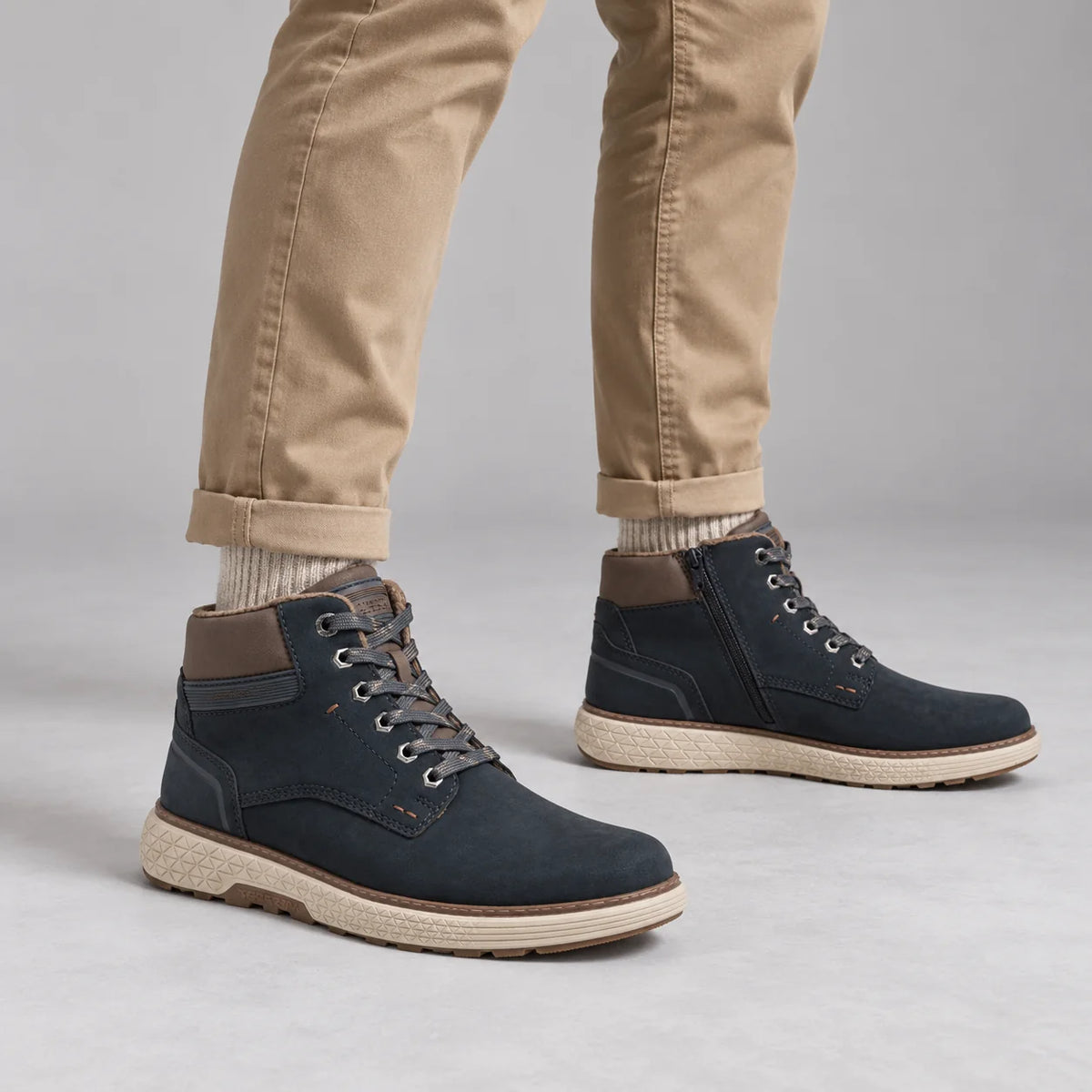 Marco Tozzi men's navy wide fit boots worn with sand chinos and oatmeal socks in a neutral grey studio.
