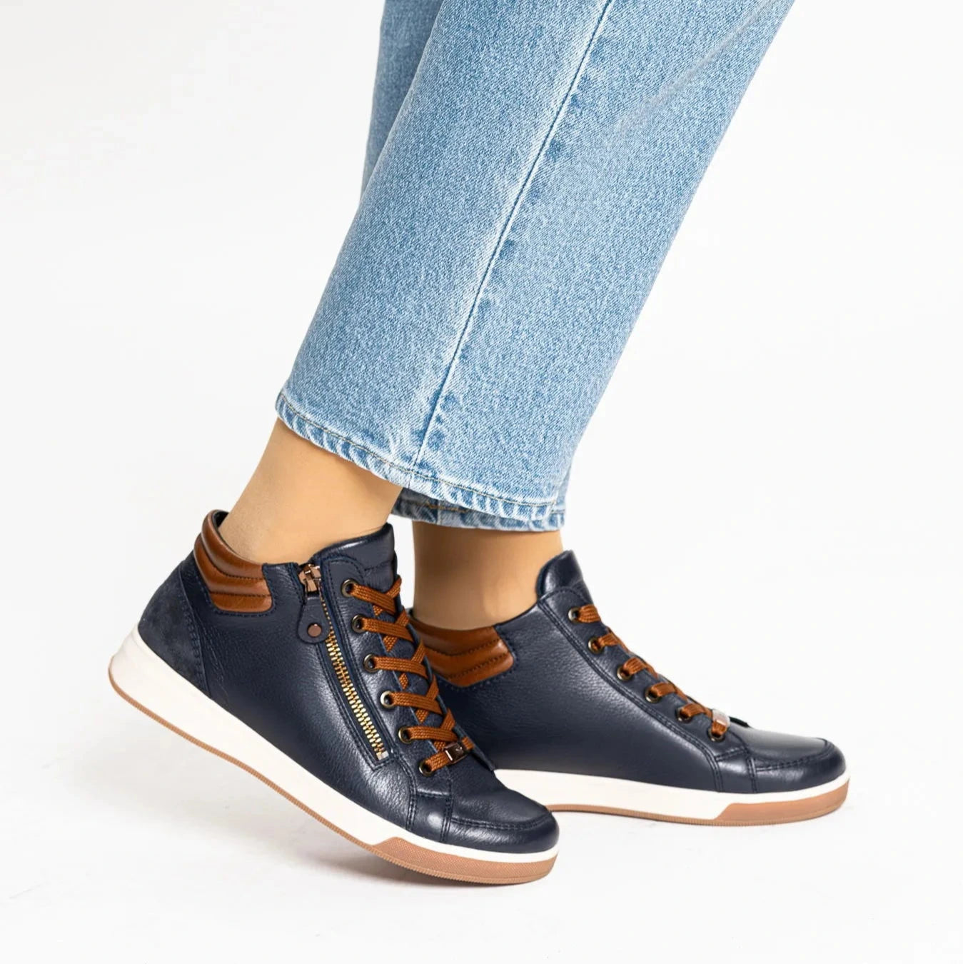 Navy high-top sneakers with brown accents worn with light blue jeans on a white background