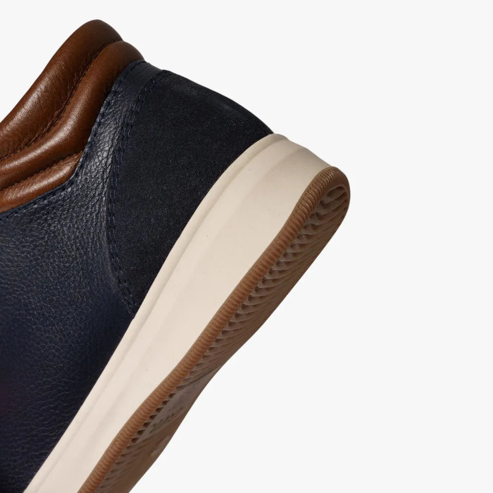Navy leather shoe with brown accents on a white background
