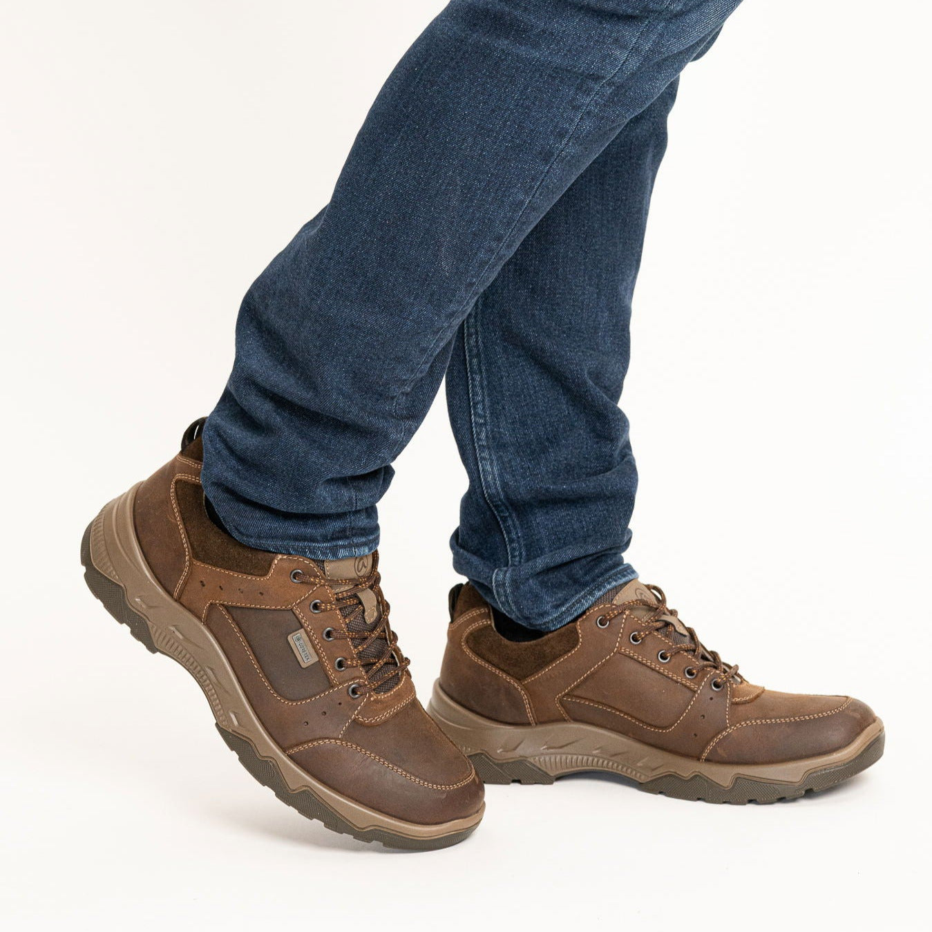 Brown hiking boots worn with blue jeans on a white background