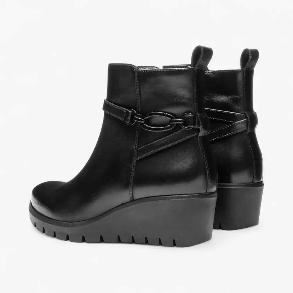 Black leather wedge boots with decorative strap on a white background