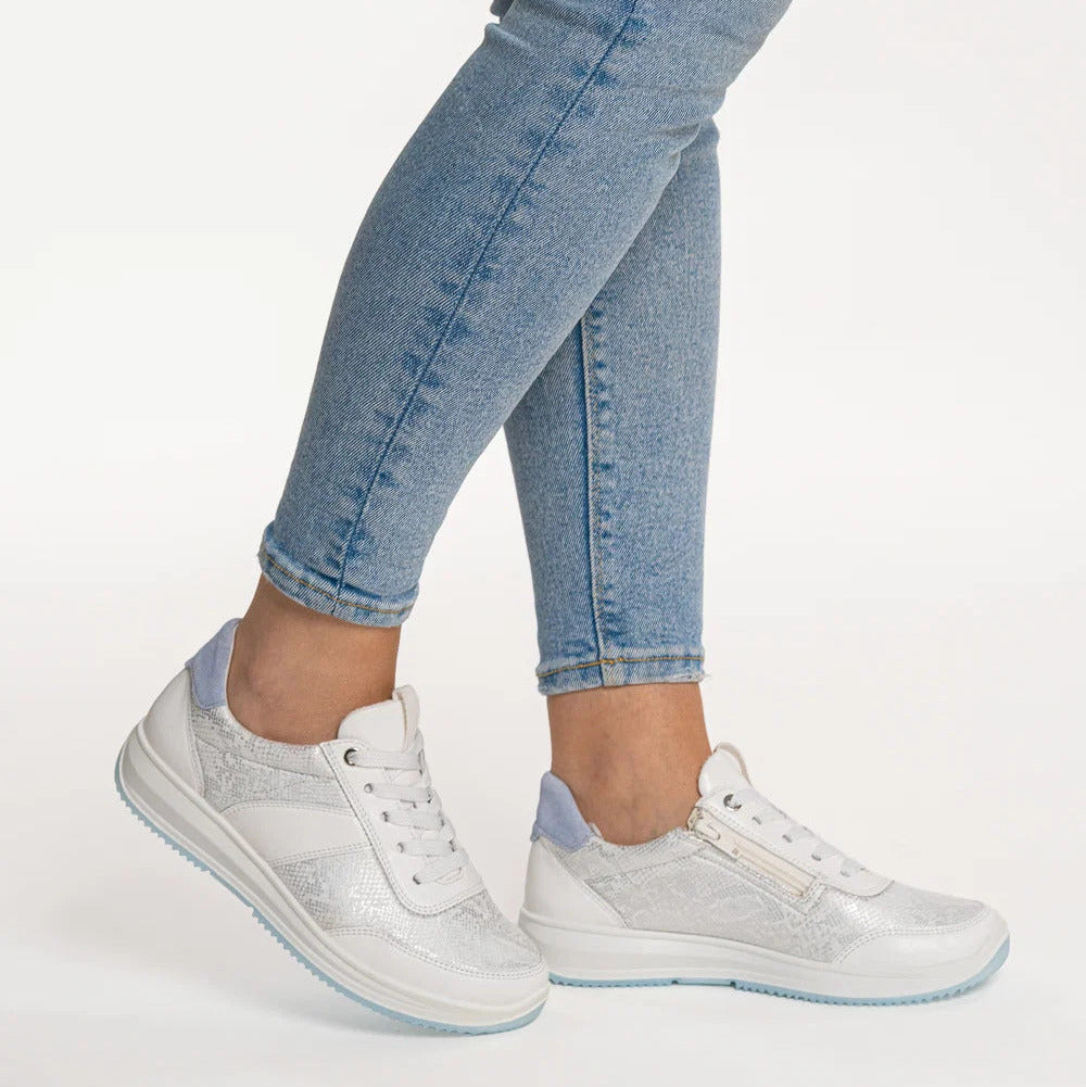 White sneakers with light blue accents worn with light blue jeans on a white background