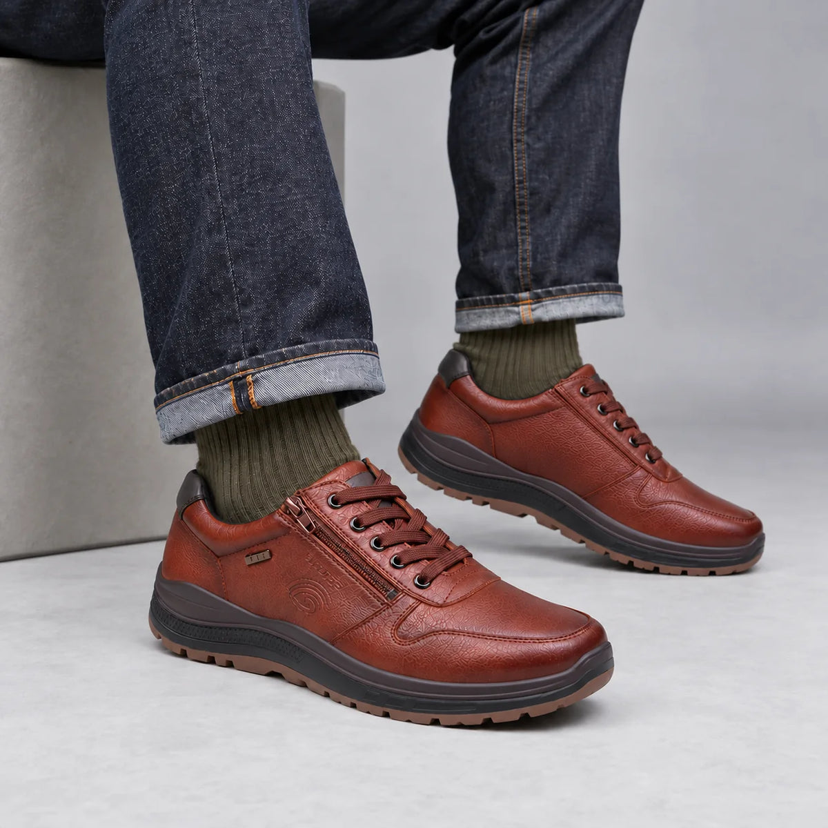 G-Comfort R-1282 men's cognac lace and zip trainers worn with dark denim and olive socks in a grey studio.