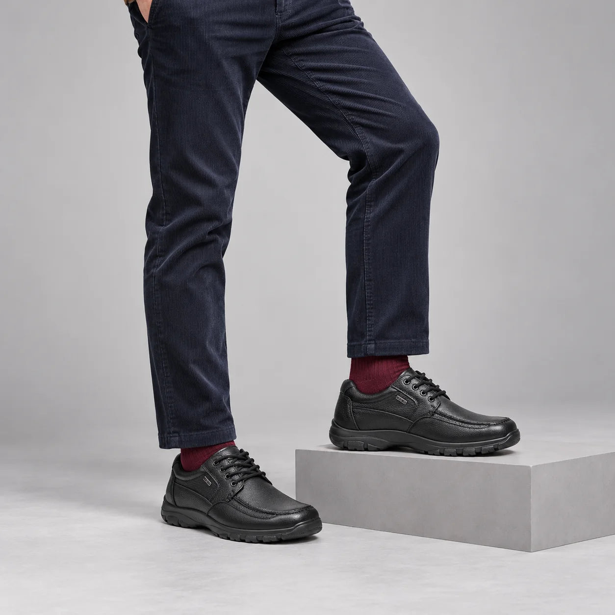 G-Comfort A-7825 men's black leather lace-up shoes styled with navy corduroys and burgundy socks in a grey studio.