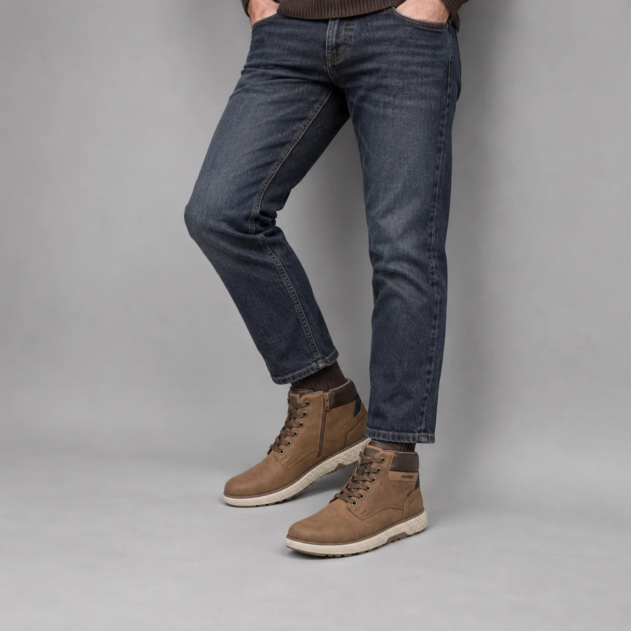 Marco Tozzi men's cognac wide fit boots worn with dark denim and brown socks in a neutral studio.