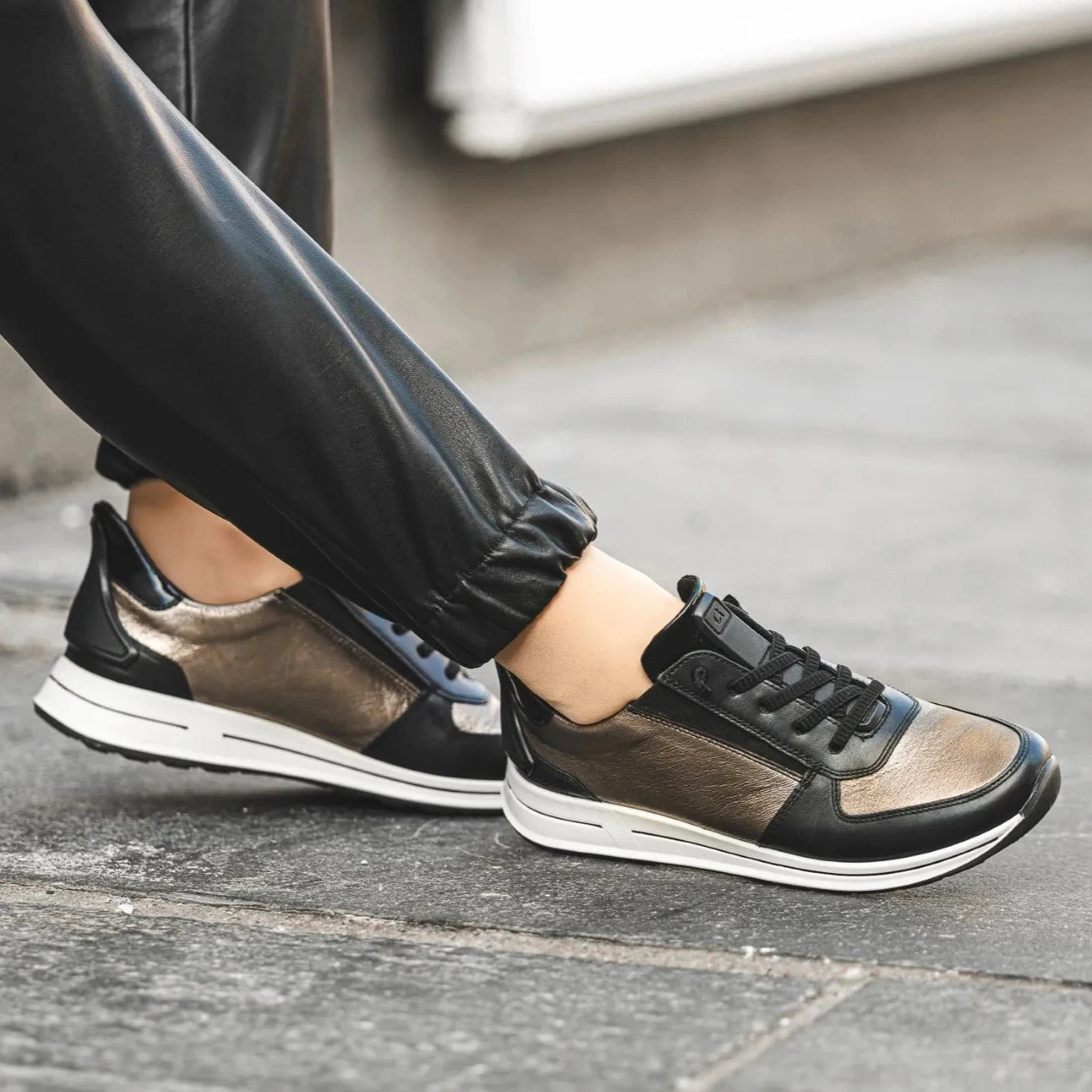 Black and brown sneakers worn on a concrete surface