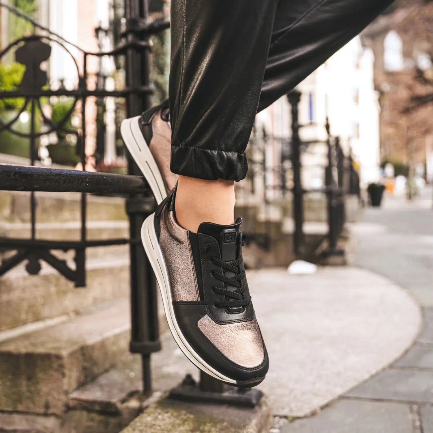 Person wearing black and white sneakers stepping onto a set of stairs.