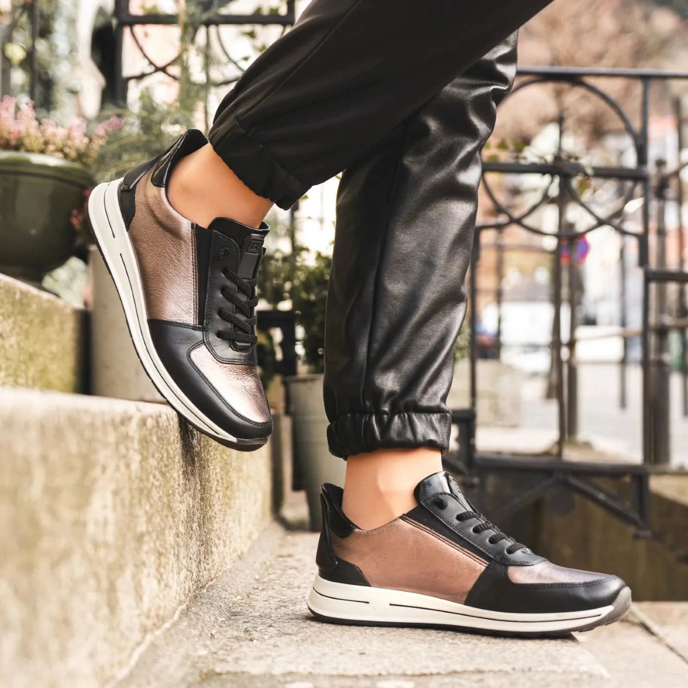 Person wearing black and brown sneakers on a city street.