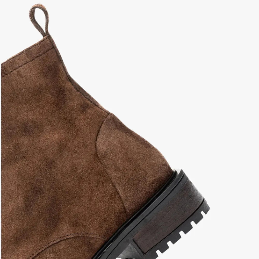 Brown suede boot with a black sole on a white background