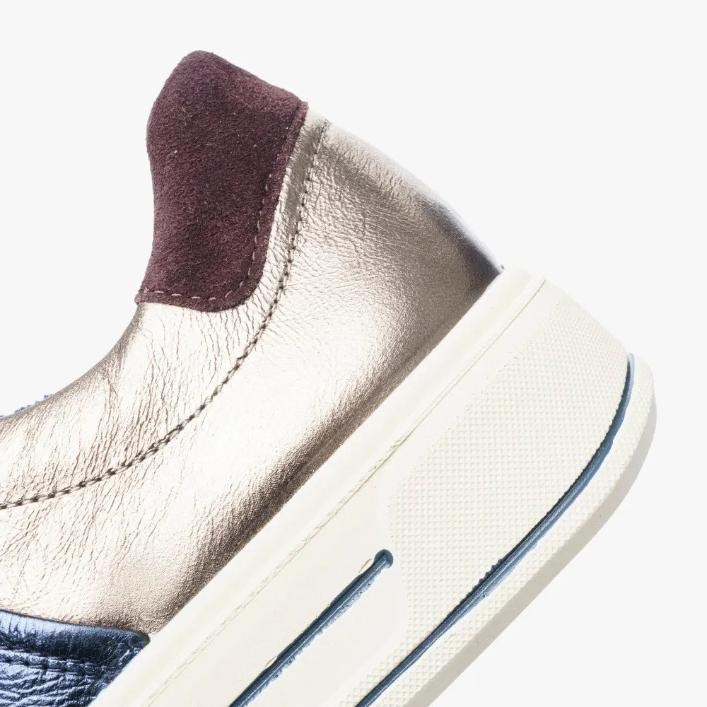 Close-up of a beige sneaker with a purple heel tab on a white background