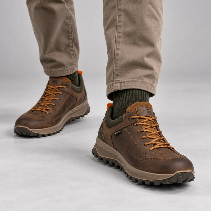 Ara Marino men's brown GORE-TEX shoes worn with taupe trousers and olive socks in a neutral grey studio.