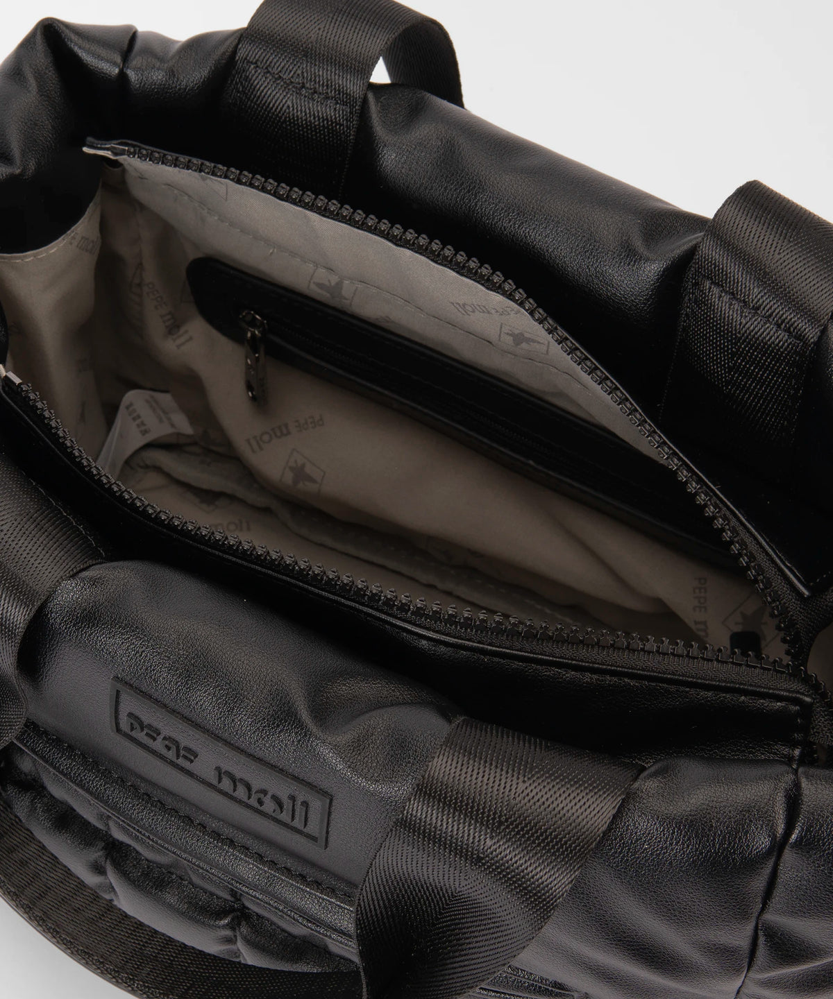 Close-up of a black backpack with visible branding on a light gray background