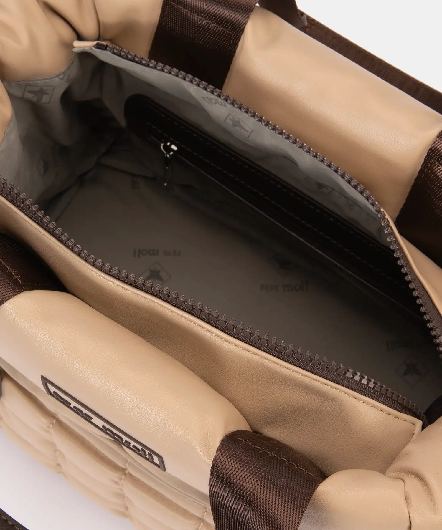 Close-up of a beige bag with a visible brand logo on a white background