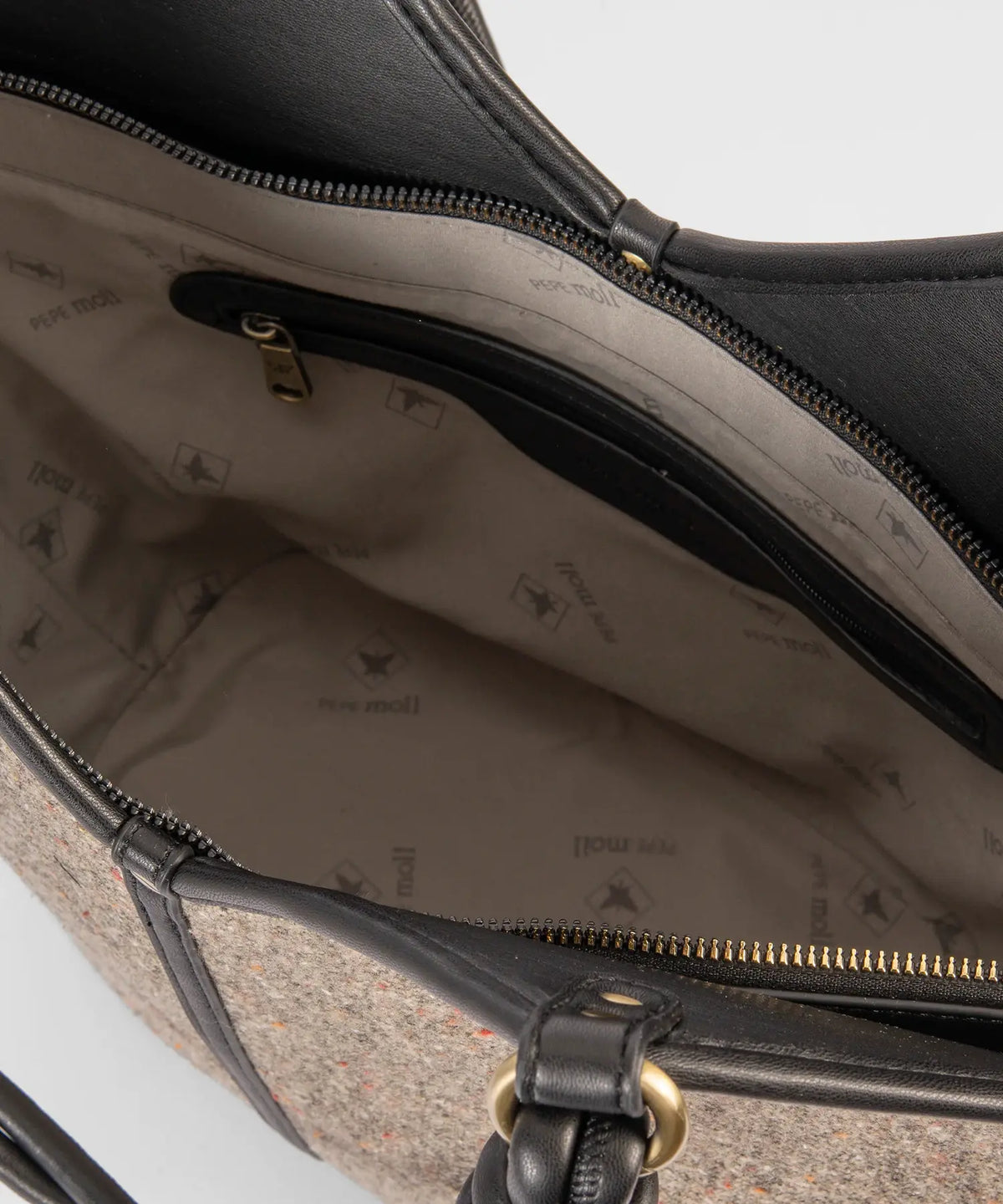 Close-up of a textured handbag with visible brand logo on a light gray background