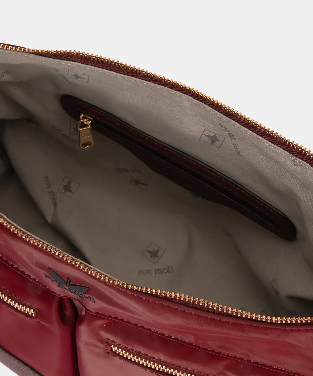 Open red handbag with gold zipper and visible brand logo on a light gray background
