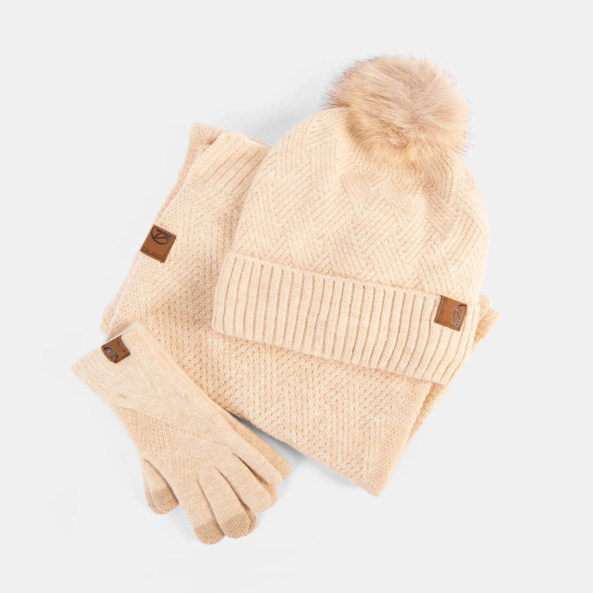 Beige knit hat with pom-pom and matching gloves on a white background