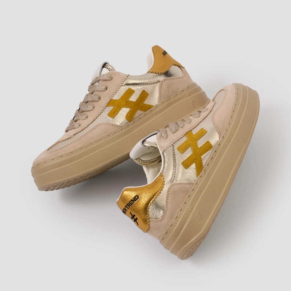 Beige sneakers with gold accents on a light gray background