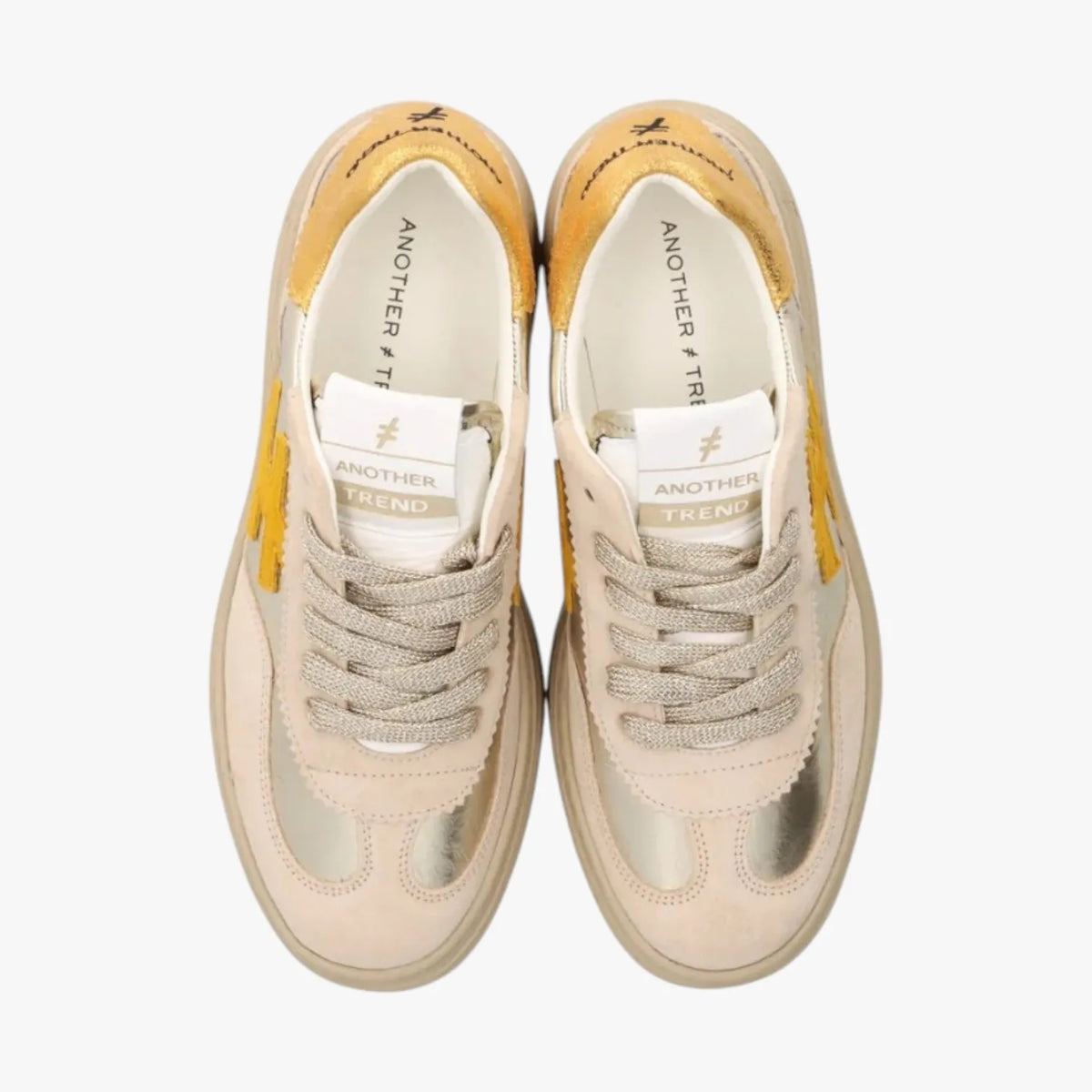 Pair of beige sneakers with yellow accents on a white background