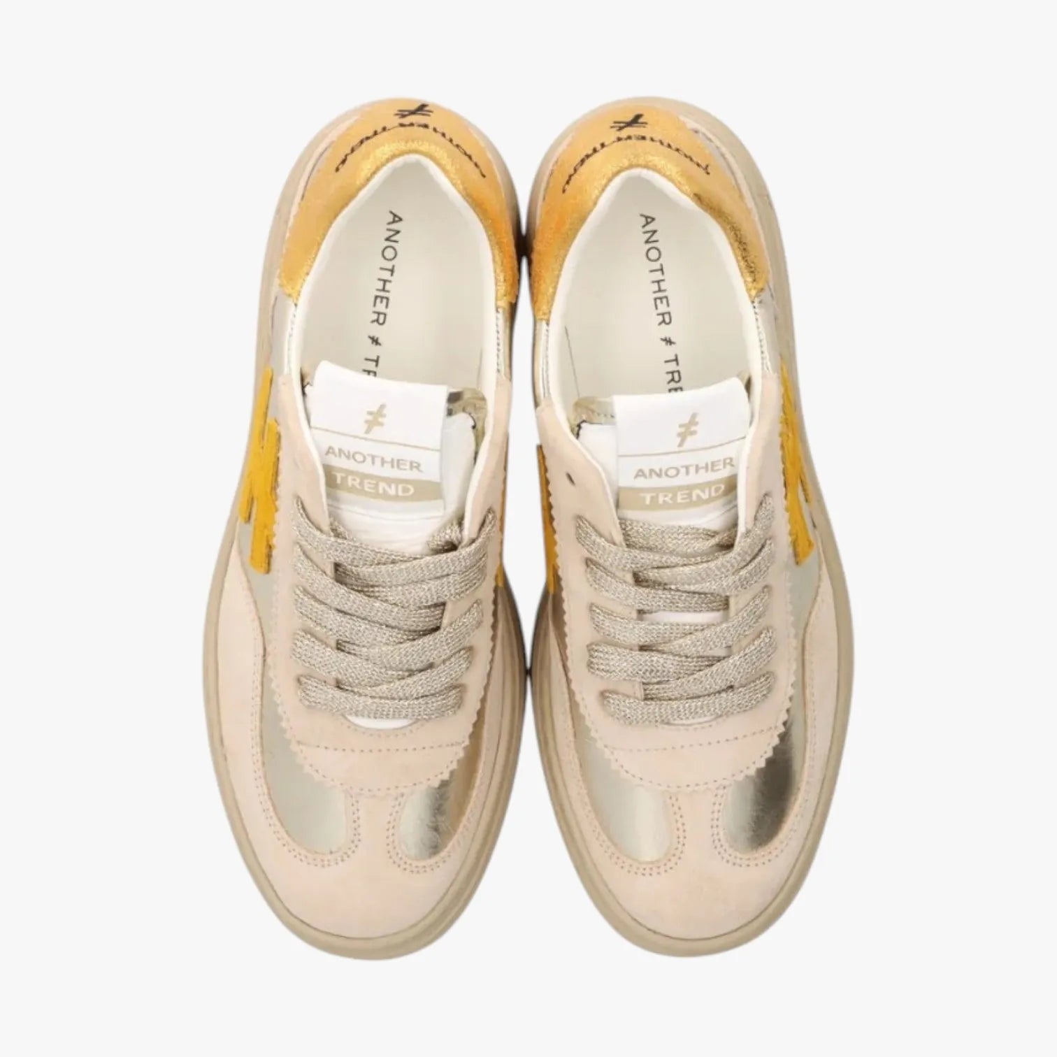 Pair of beige sneakers with yellow accents on a white background