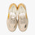 Pair of beige sneakers with yellow accents on a white background